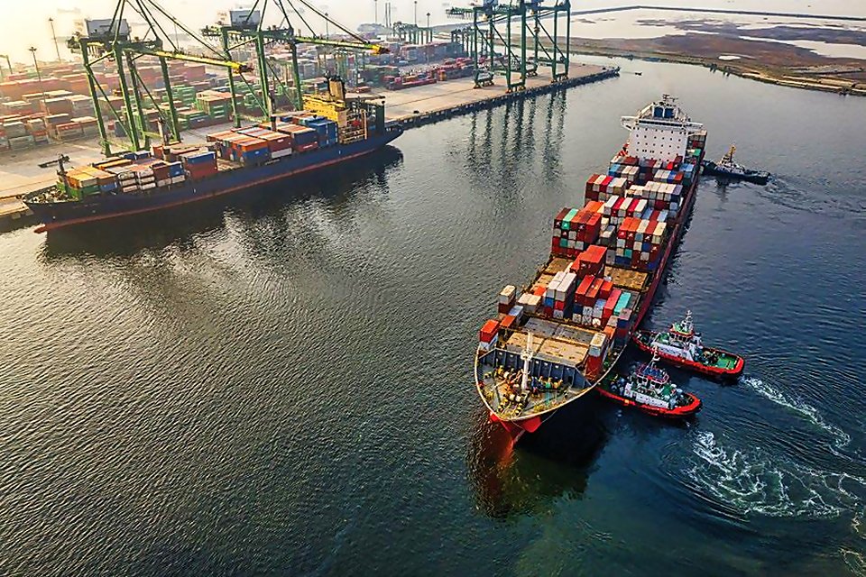 A container ship guided into port by tugboats
